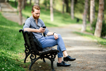 英俊的家伙在公园里使用手机