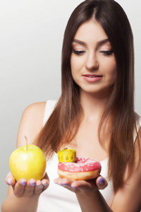 一个年轻的女人在健康和有害的食物之间做出选择。s