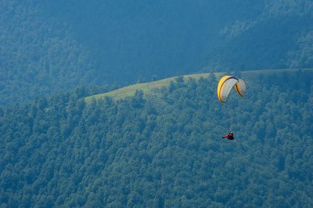 在阳光明媚的夏日，滑翔伞飞过一个山谷