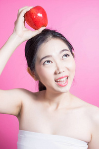 亚洲妇女与苹果概念。她笑着抱着苹果。美丽的脸庞和自然的妆容。在粉红色背景上隔离