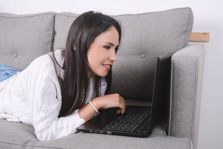 女人在沙发上使用便携式计算机