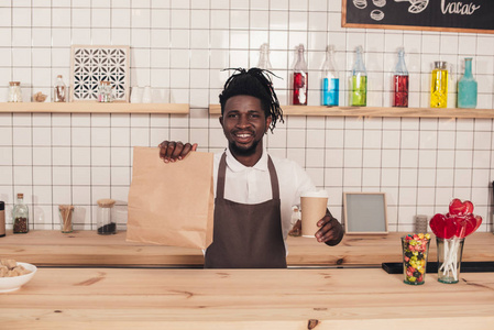 非裔美国人咖啡师在酒吧柜台端着一次性咖啡和卡夫包装