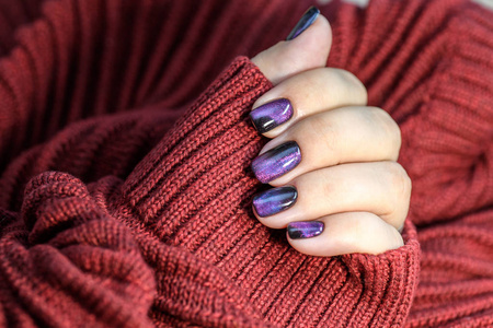 美丽的指甲油在手紫色指甲艺术指甲修剪红色背景。