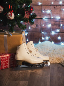 女人溜冰鞋在一个旧的皮皮箱和一棵圣诞树旁边。圣诞装饰品