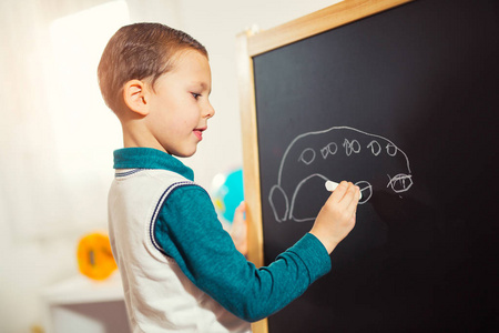 幼稚的涂鸦，小男孩用粉笔在黑板上画画