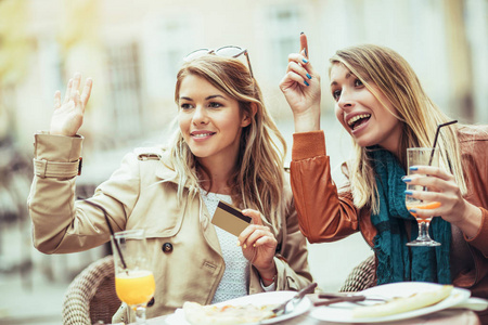 两名年轻妇女在餐馆用信用卡付账的肖像