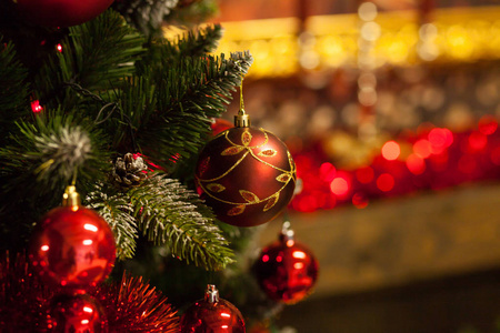 新的一年人造圣诞树装饰着五颜六色的明亮的球在一个模糊的红色背景。圣诞背景