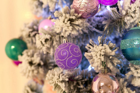新的一年人造圣诞树装饰着五颜六色的明亮的球在一个模糊的灯光背景。圣诞背景