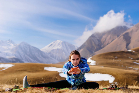 运动年轻的女孩旅行者在高加索山脉的背景下从事瑜伽