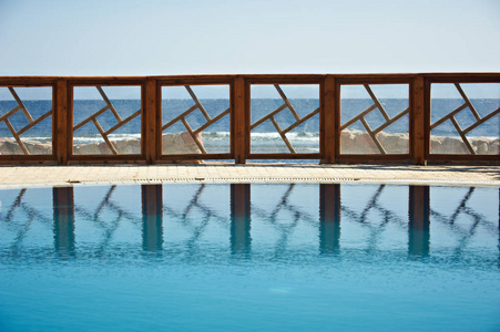 度假村水池的栅栏倒映在水面上。纯净的蓝天在背景