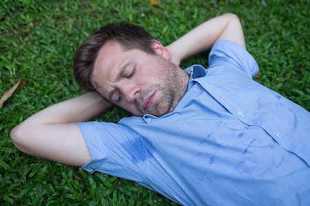 白种人, 年轻人在绿色的草地上休息, 看着他的湿衬衫