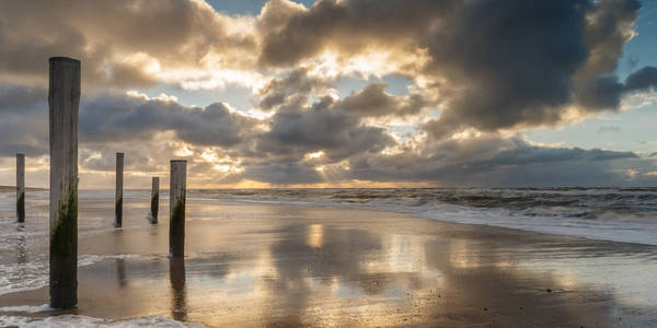在日落和强风的时候，荷兰皮特顿海滩上的两根柱子是沙滩上的一件艺术品