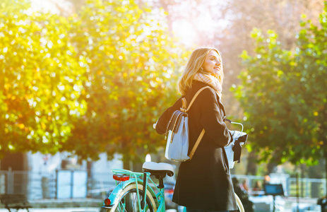 秋天在城市的妇女与古董自行车