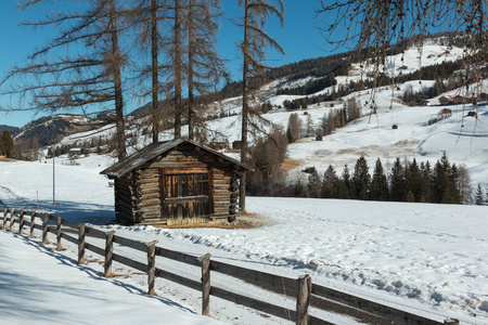 小木屋和篱笆间树木在冬季的一天与新鲜的雪在山上