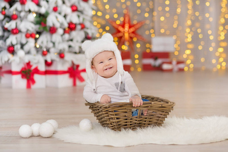 美丽的小男婴庆祝圣诞节。新年假期。婴孩在圣诞节服装休闲衣裳与礼物在毛皮附近到新年树在演播室装饰