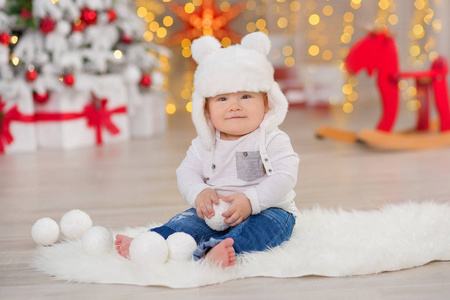 美丽的小男婴庆祝圣诞节。新年假期。婴孩在圣诞节服装休闲衣裳与礼物在毛皮附近到新年树在演播室装饰