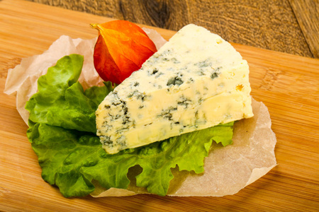 木制背景上有沙拉叶的蓝色奶酪
