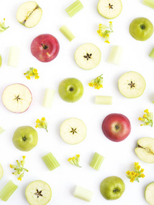 绿色和红色苹果的图案。 白色背景上的水果和花。 水果的壁纸。 切片苹果的组成.俯视图平躺