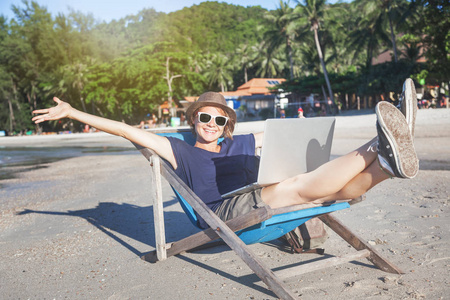 年轻漂亮的女人时髦旅行者自由职业者的笔记本电脑上