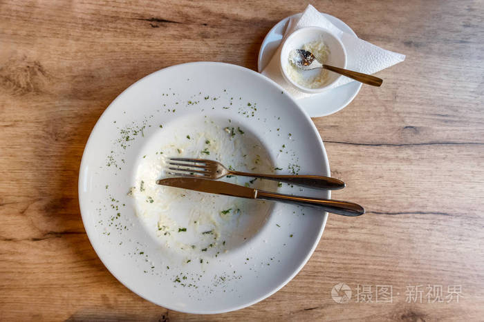 餐后用餐叉和食物残渣的空盘子放在木桌上