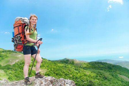 绿色山顶上背包的快乐徒步旅行女人