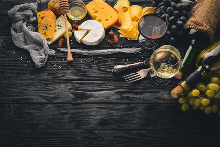 木制桌子上有各种各样的奶酪布里奶酪戈贡佐拉蓝色奶酪葡萄蜂蜜坚果红白葡萄酒。上景。免费的文本空间。