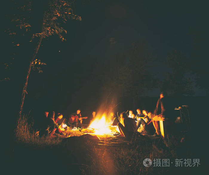 年轻人的公司围坐在篝火旁