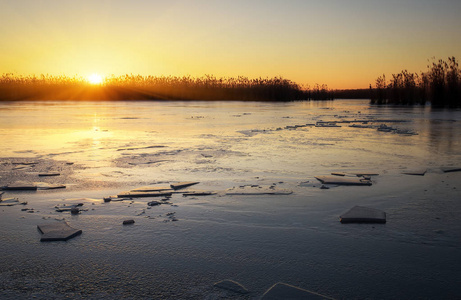 用冰冻的河面 芦苇和落日的天空的冬季景观。黎明