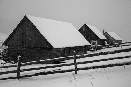 村庄的全景在冬天的山上覆盖着雪。 冬季景观。 自由和孤独的概念。