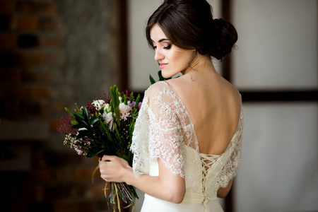 优雅的新娘手里拿着花束。穿白色裙子的美丽新娘的肖像