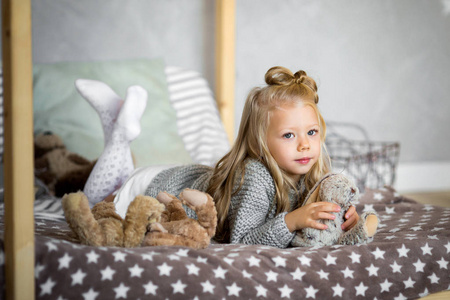 可爱的小女孩正在玩一只玩具熊在床上