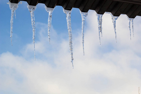 冬天屋顶上挂着冰柱。冬季屋顶边缘冰晶体的天然冰形成