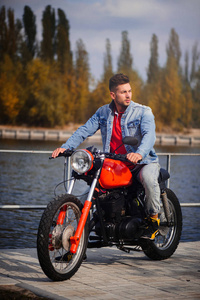 年轻的体育时尚男子骑摩托车, 一个温暖的镜头, 深秋
