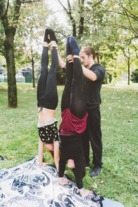 男人教两个女孩如何在秋天的公园里户外倒立