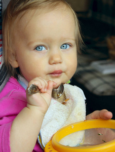 儿童健康营养概念。 快乐的小白种人女孩吃汤，她嘴里有勺子。 蓝眼睛的女婴