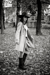 戴着时髦帽子摆着秋装公园的迷人年轻女子