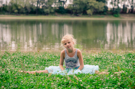 小女孩坐在河边的草地上