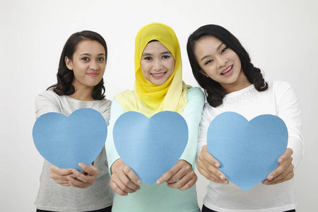 三个多种族的马来西亚人拿着心形纸板看相机