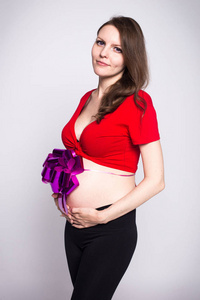 一个穿着红色短衫带着蝴蝶结的小肚子的怀孕少女