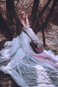 美丽浪漫欧洲女孩与吉他与花里面, 摆在户外。音乐和自然的概念。春季时间