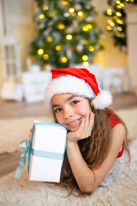 快乐的小女孩，微笑着与附近的圣诞节树上的礼品盒。圣诞节概念