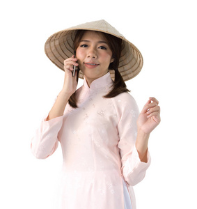 美丽的女人在粉红色的礼服和越南帽子持有智能手机