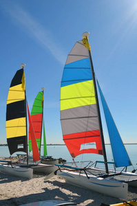 佛罗里达州比斯坎湾海滩上的一艘小双体船，彩色的帆停在沙滩上