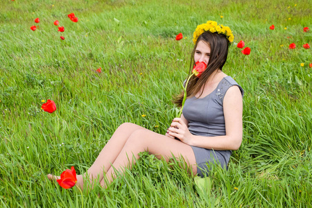 美丽的仙女少女在郁金香花丛中的田野里。 一个女孩在红花和绿色田野背景上的肖像。 郁金香领域。