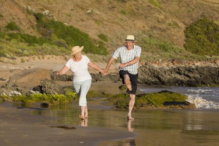 可爱的高级成熟夫妇在他们的60s 或70s 退休步行愉快和放松在海滩海边在浪漫的老龄化一起