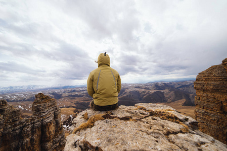 一个人坐在悬崖边上, 看着群山, 享受大自然