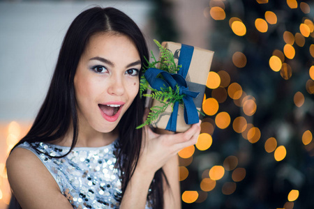 美丽兴奋的微笑年轻女子与礼物的礼物感觉幸福的圣诞树附近。特写肖像