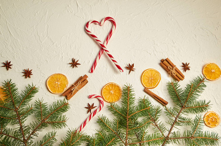新年食品装饰与冷杉枝，红色糖果锥的心脏和传统香料覆盖葡萄酒八角星，肉桂棒，干橙子在白色混凝土背景。一般看法