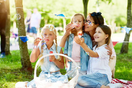 无忧无虑的孩子和他们的母亲在公园里玩肥皂泡的乐趣