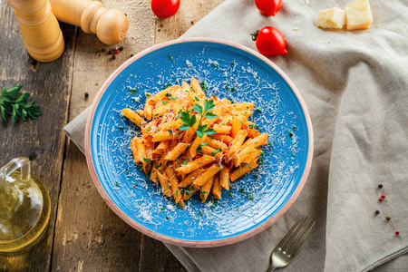 传统的意大利彭尼面食与Arrabiata番茄酱在一个蓝色的乡村盘子。 美味健康的地中海美食。 上面的风景。